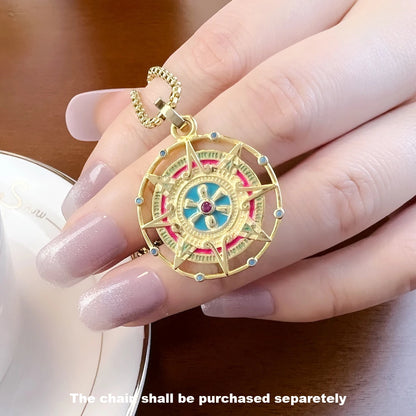 Goldfarbener Anhänger in Hand gehalten, rundes Azteken-Motiv mit bunten Steinen