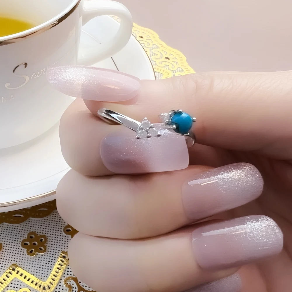 Silberner Ring mit türkisblauem Stein, flankiert von Zirkonia