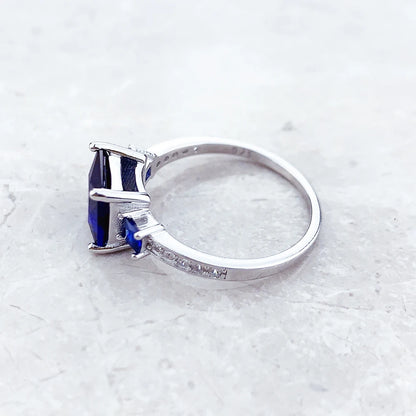 Silberner Cocktailring mit quadratischem blauem Stein und funkelnden Fassungen