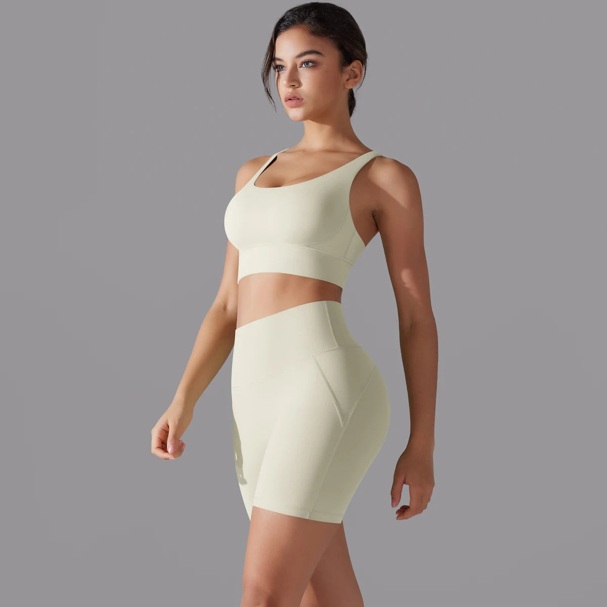 Nahtloses Fitnessset für Damen: helles, cremefarbenes Sporttop und kurze Leggings
