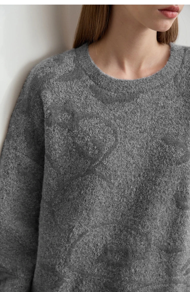 Nahaufnahme: grauer Damenpullover mit O-Ausschnitt, feiner Jacquard-Strickstruktur