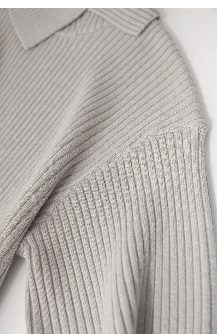 Nahaufnahme: Grau-beiger Strickpullover mit gerippter Schulterpartie und Ärmelabschlüssen