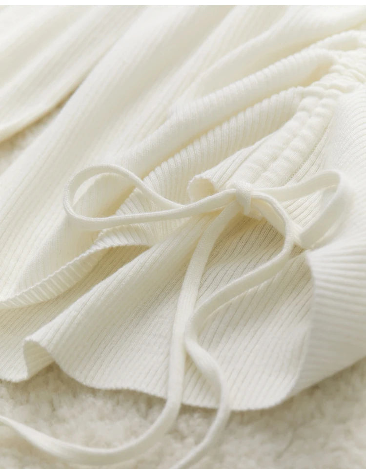 Cremefarbene Kordel mit Schleife am V-Ausschnitt des Strickpullovers