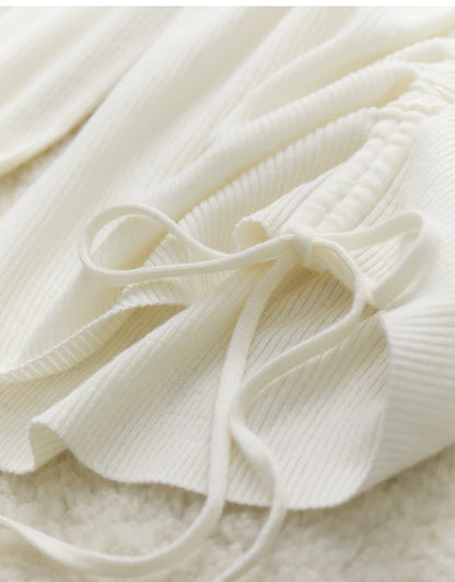 Cremefarbene Kordel mit Schleife am V-Ausschnitt des Strickpullovers