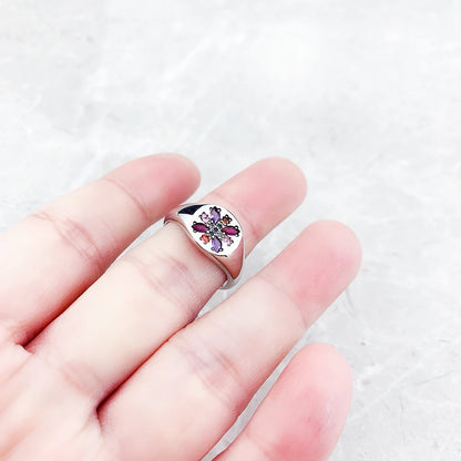Silberring mit kleinem farbigen Blumensteinmotiv auf dem Ringkopf