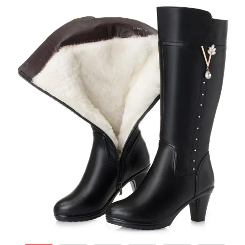 Schwarze kniehohe Damenstiefel mit geöffnetem Wollfutter und Blüten-Zieranhänger am Schaft.