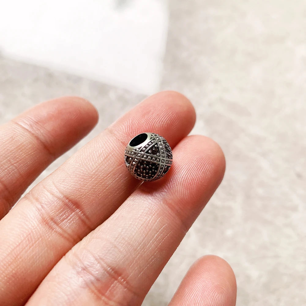 Silberne Charms-Perle mit schwarzem Zentrum und geometrischem Muster, auf Finger