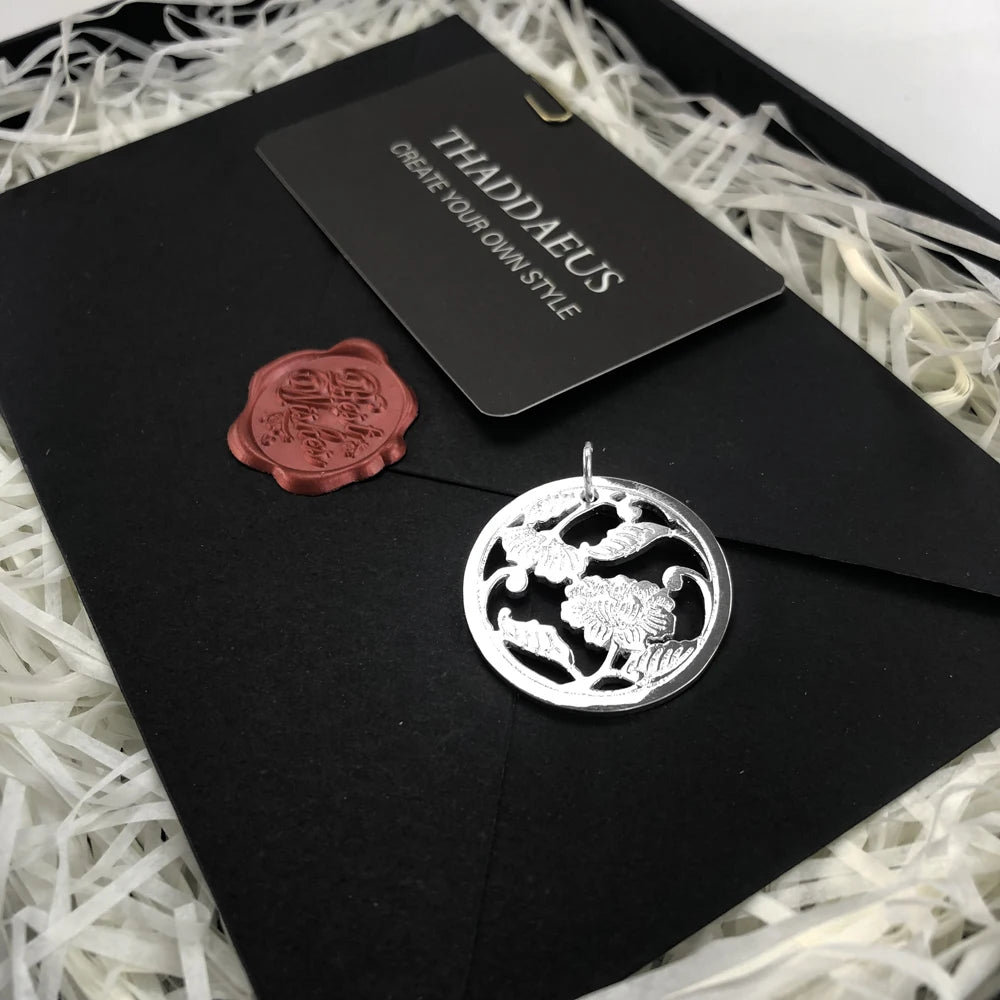 Runder Anhänger aus silberfarbenem 925 Sterlingsilber mit Blumenrelief auf schwarzer Karte