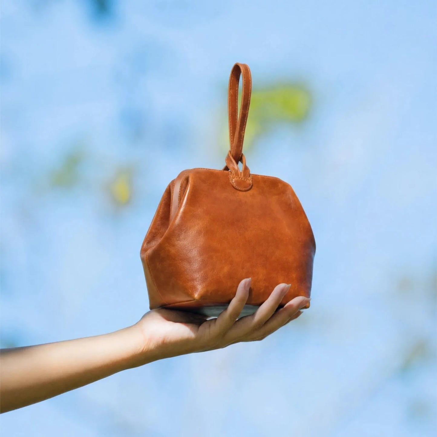 Kleine braune Ledertasche mit abgerundetem Beutel und kurzem Henkel