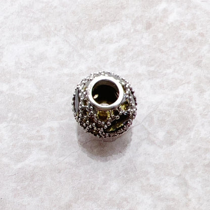 Charme aus silberfarbenem Metall mit gelb-grünen Steinen, Rückseite mit Öffnung