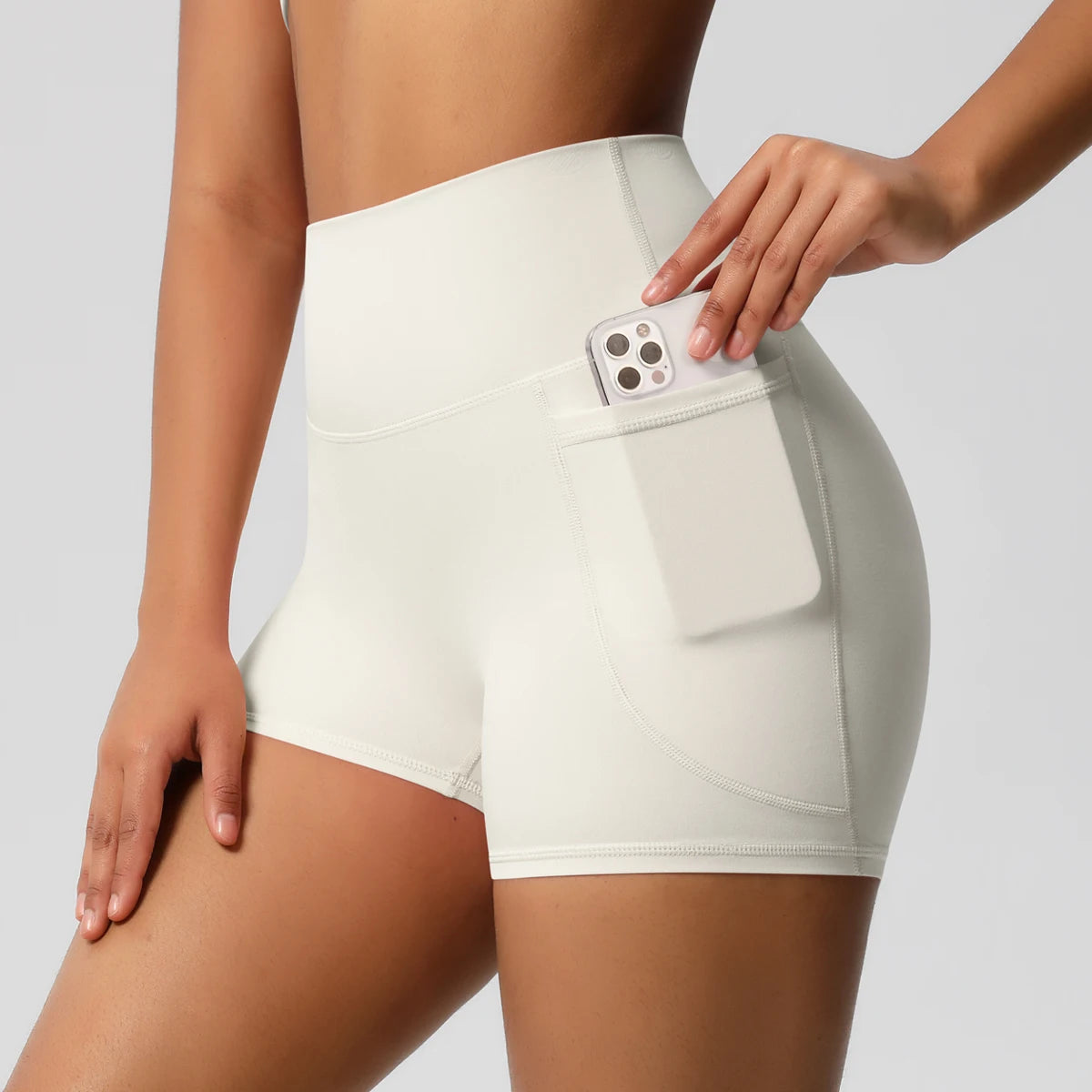 Damen-Yogashorts hohe Taille mit Seitentaschen, hellbeige, mit eingestecktem Handy