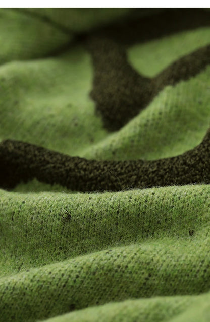 Nahaufnahme des grünen Stricks mit schwarzem Jacquardmuster und Rippenborte