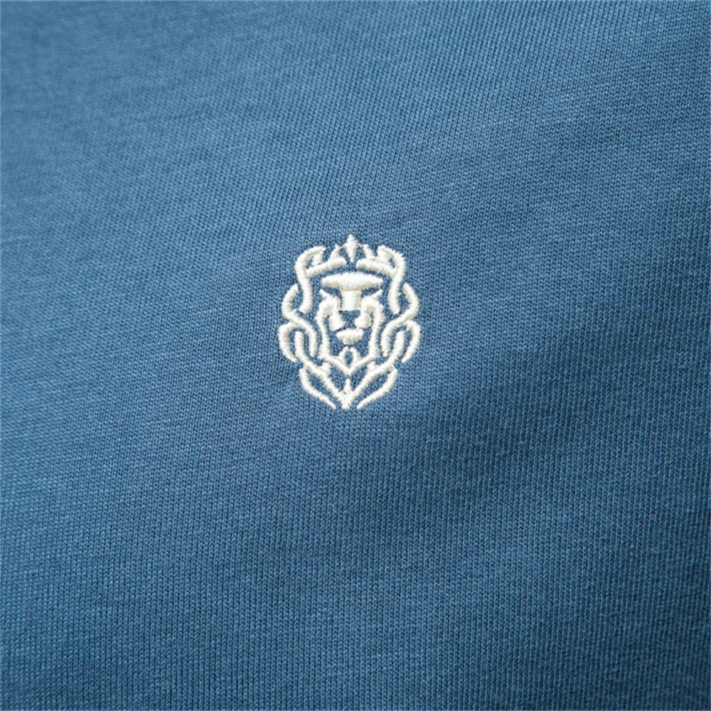 Detailaufnahme: gesticktes Brustlogo auf blauem Stoff des Herren-T-Shirts.