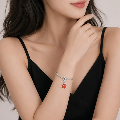 Silbernes Armband mit rotem Fischanhänger am Handgelenk, feine Kette