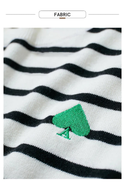 Strickstoff mit schwarz-weißen Streifen und grüner Bestickung am Pullover